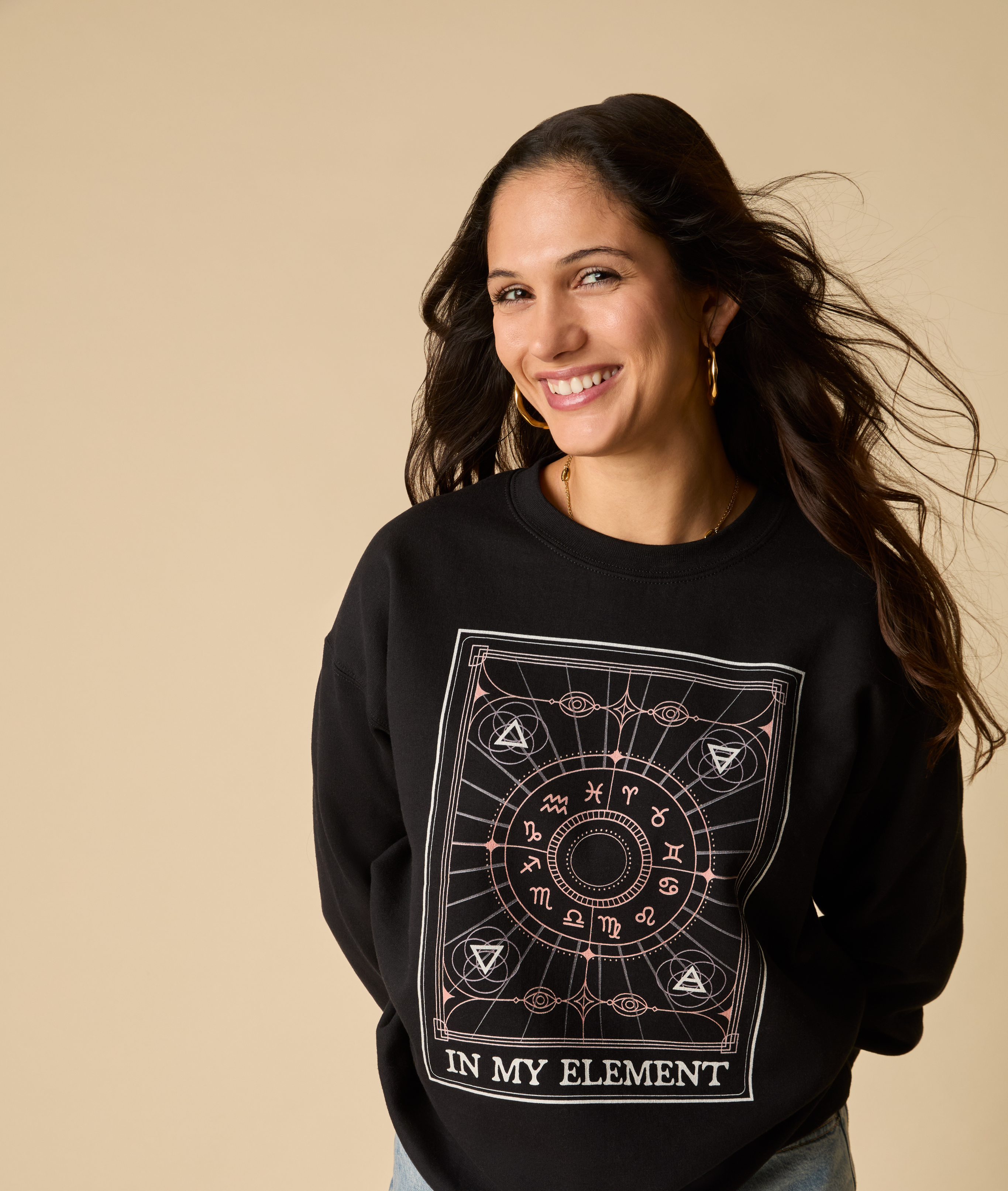 Woman wearing a black sweatshirt with a design and text on a beige background